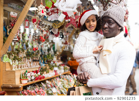 Man with small daughter looking around at Christmas fair Man with small daughter looking around at Christmas fair 92901235
