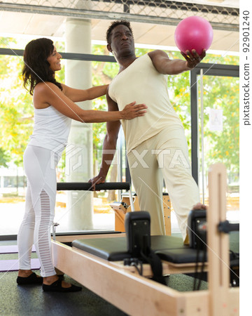 Experienced Latin female instructor helping African-American man during training 92901240