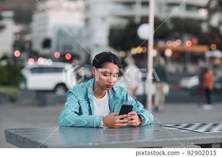 Depressed, sad and bored woman with phone waiting and reading texts after being stood up on sunset city date. Annoyed, anti social and lonely student checking and browsing social media on technology Depressed, sad and bored woman with phone waiting and reading texts after being stood up on sunset city date. Annoyed, anti social and lonely student checking and browsing social media on technology 92902015