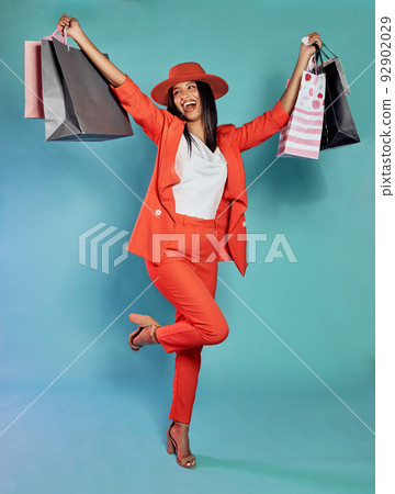 Excited and trendy woman with shopping bags after retail therapy, spending and buying clothes. Stylish, edgy and funky model holding gifts and wearing colorful, fashionable red suit while happy Excited and trendy woman with shopping bags after retail therapy, spending and buying clothes. Stylish, edgy and funky model holding gifts and wearing colorful, fashionable red suit while happy 92902029