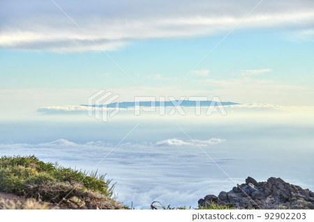 Hiking mountain to view volcano through dense cloud cover in travel or tourism destination. Exploring scenic background skyscape of Roque de Los Muchachos, La Palma, Canary Islands, Spain from above 92902203