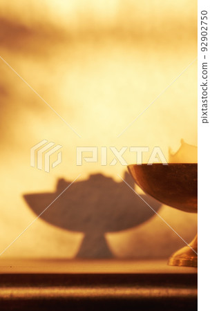 Closeup of lit candle, a symbol of hope, truth or spiritual in brass holder lighting and illuminating dark home room with copy space. Antique decor on a wooden table for aroma, scent and harmony Closeup of lit candle, a symbol of hope, truth or spiritual in brass holder lighting and illuminating dark home room with copy space. Antique decor on a wooden table for aroma, scent and harmony 92902750