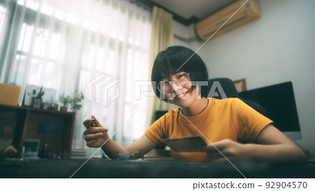 Young adult asian woman playing board game on top table at home. 92904570