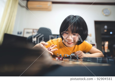Young adult asian woman playing board game on top table at home. 92904581