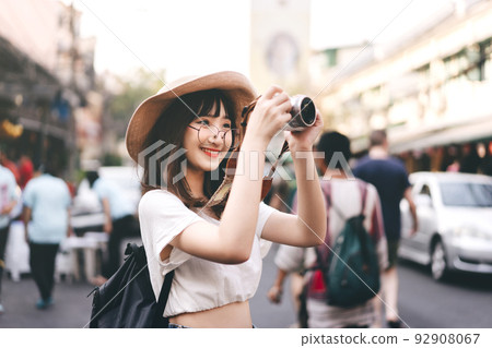 Young asian woman traveller take a photo by camera at khaosan street road. 92908067