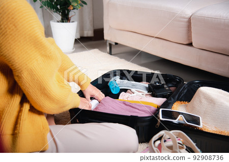 Woman packing clothes in luggage for new journey Woman packing clothes in luggage for new journey 92908736