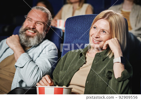 Selective focus of mature Caucasian woman and her husband spending time together watching interesting movie at cinema 92909556