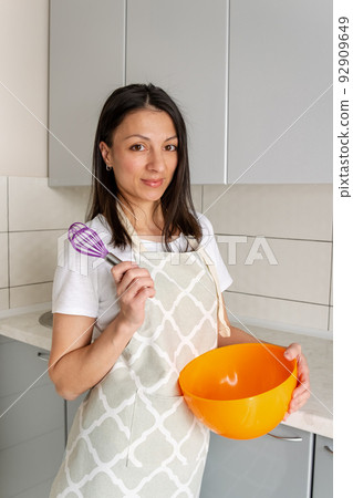 Smiling woman using whisk. Happy chef whisking cream. 92909649