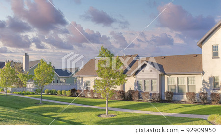 Panorama Puffy clouds at sunset Row of houses with lawn and two concrete walkways on the sides a 92909950