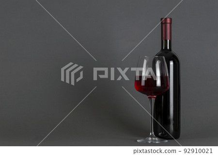 Red wine bottle and glass on a gray background. Wine drinking culture concept. 92910021