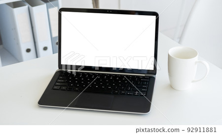 Online technology. Computer mockup. Distance work. Opened laptop with blank screen staying on desk with cup of coffee in light room interior. Online technology. Computer mockup. Distance work. Opened laptop with blank screen staying on desk with cup of coffee in light room interior. 92911881