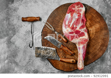Raw lamb shoulder on butcher's cutting log with tools Raw lamb shoulder on butcher's cutting log with tools 92912091