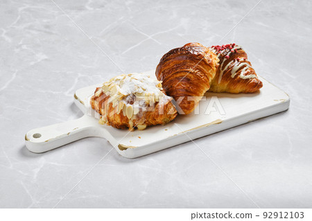 Assortment of fresh croissants on serving board on marble background Assortment of fresh croissants on serving board on marble background 92912103