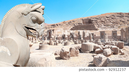 Stone sculpture of griffin and Ruins of Palace of 100 columns and tomb of Artaxerxes III, Persepolis, Iran Stone sculpture of griffin and Ruins of Palace of 100 columns and tomb of Artaxerxes III, Persepolis, Iran 92912237