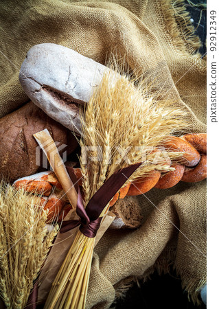 Top view of a bouquet of wheat lying on fresh bread and other bakery products as a symbol of food and agrarian well-being of the country Top view of a bouquet of wheat lying on fresh bread and other bakery products as a symbol of food and agrarian well-being of the country 92912349