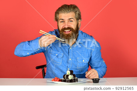 dinner at home. hipster eat sushi with chopsticks. tasty sushi roll. traditional and healthy food in japan. japanese sushi dish. man eating traditional Japanese food with chopsticks dinner at home. hipster eat sushi with chopsticks. tasty sushi roll. traditional and healthy food in japan. japanese sushi dish. man eating traditional Japanese food with chopsticks 92912565
