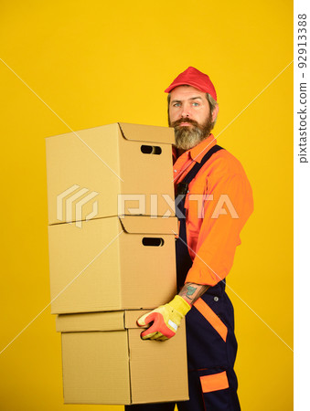 Man wearing boilersuit packing boxes. move to new apartment. bearded loader in uniform. Cardboard boxes - moving to a new house. purchase of new habitation or repair of room Man wearing boilersuit packing boxes. move to new apartment. bearded loader in uniform. Cardboard boxes - moving to a new house. purchase of new habitation or repair of room 92913388