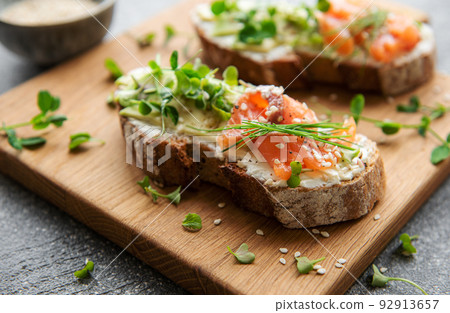 Sandwiches with salted salmon, avocado and microgreens. Sandwiches with salted salmon, avocado and microgreens. 92913657