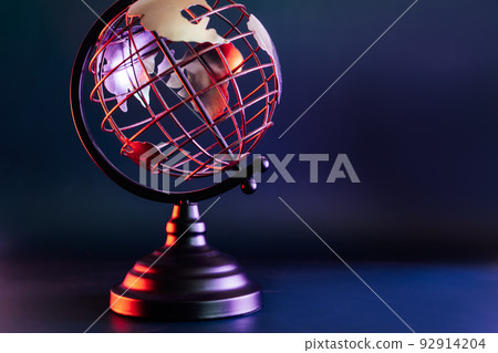 Close up metallic model of a globe with map in blue and red neon light. Bipolarity of the world. Geography concept. Selective focus, Copy space. 92914204