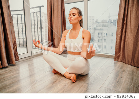 Young woman meditating at home. Girl practicing yoga in class. Relaxation at home, body care, balance, healthy lifestyle, meditation, mindfulness, recreation, workout, fitness, training concept Young woman meditating at home. Girl practicing yoga in class. Relaxation at home, body care, balance, healthy lifestyle, meditation, mindfulness, recreation, workout, fitness, training concept 92914362