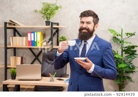 happy bearded businessman drinking coffee in the office with copy space, morning happy bearded businessman drinking coffee in the office with copy space, morning 92914439