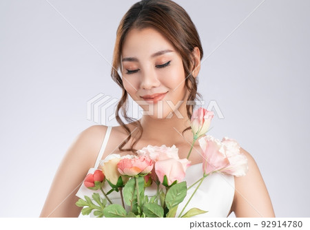 Gorgeous female model with fair skin and perfect makeup holding flowers. Gorgeous female model with fair skin and perfect makeup holding flowers. 92914780