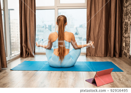 Young woman meditating at home. Girl practicing yoga in class. Relaxation at home, body care, balance, healthy lifestyle, meditation, mindfulness, recreation, workout, fitness, training concept Young woman meditating at home. Girl practicing yoga in class. Relaxation at home, body care, balance, healthy lifestyle, meditation, mindfulness, recreation, workout, fitness, training concept 92916495