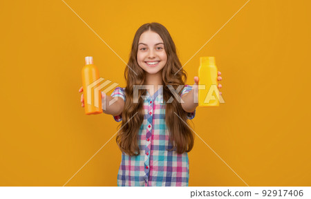 cheerful child with hair conditioner bottle on yellow background cheerful child with hair conditioner bottle on yellow background 92917406