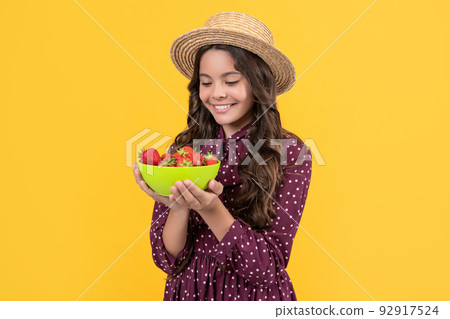 happy teen kid hold strawberry bowl on yellow background happy teen kid hold strawberry bowl on yellow background 92917524