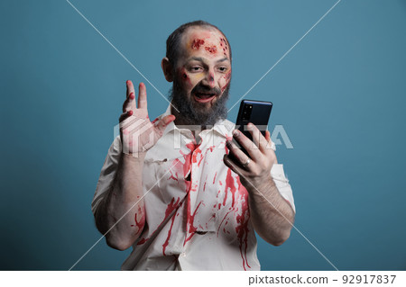 Terrifying zombie using videocall conference on smartphone, trying to talk on remote videoconference call and looking creepy. Deadly monster and brain eating corpse using teleconference. Terrifying zombie using videocall conference on smartphone, trying to talk on remote videoconference call and looking creepy. Deadly monster and brain eating corpse using teleconference. 92917837