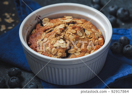 Vegan oatmeal, banana, blueberry mug muffin on blue background. Plant based dessert. Vegan oatmeal, banana, blueberry mug muffin on blue background. Plant based dessert. 92917864