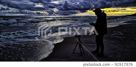 Sunset over Baltic Sea with photographer and oil platform in background - Lubiatowo, Poland Sunset over Baltic Sea with photographer and oil platform in background - Lubiatowo, Poland 92917876