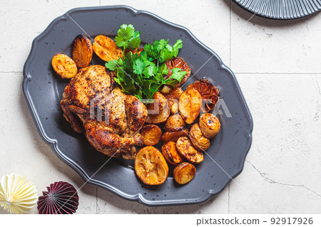 Christmas baked chicken with potatoes on gray plate. Festive homemade food concept. Christmas baked chicken with potatoes on gray plate. Festive homemade food concept. 92917926
