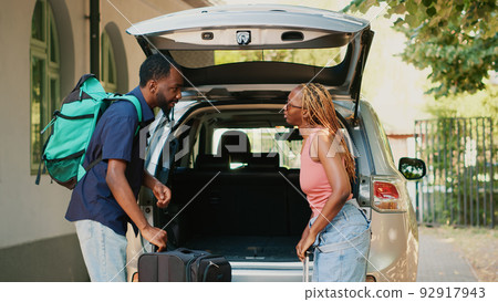 Married people putting baggage inside vehicle while going on field trip. Couple loading voyage luggage and trolleys inside car trunk while getting ready for holiday citybreak departure 92917943