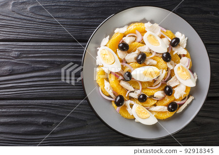 Remojon is a traditional Spanish salad made with a combination of oranges, salt cod, eggs, olive oil, olives, and wine vinegar close-up in a plate. Horizontal top view Remojon is a traditional Spanish salad made with a combination of oranges, salt cod, eggs, olive oil, olives, and wine vinegar close-up in a plate. Horizontal top view 92918345