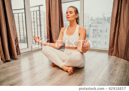Young woman meditating at home. Girl practicing yoga in class. Relaxation at home, body care, balance, healthy lifestyle, meditation, mindfulness, recreation, workout, fitness, training concept 92918857