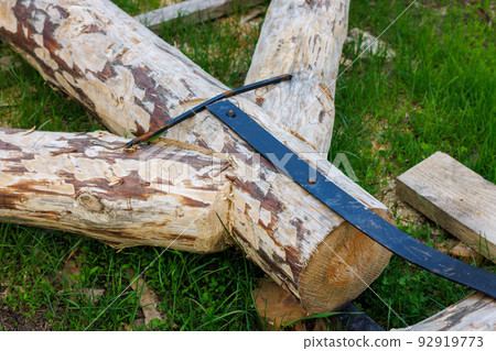 forged steel stripe connection of wooden log beams for roof support girder framework laid on green grass at summer day forged steel stripe connection of wooden log beams for roof support girder framework laid on green grass at summer day 92919773