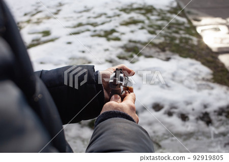 A man reloads a gun in a dash outside the door. Winter. A man reloads a gun in a dash outside the door. Winter. 92919805