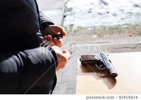 A man charges a gun with bullets in the street. Danger, murder, firearms, shooting range, sports entertainment. A man charges a gun with bullets in the street. Danger, murder, firearms, shooting range, sports entertainment. 92919824