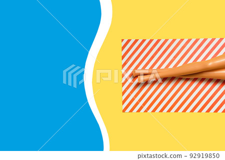 Summer vacation layout with doll legs on beach towels, flat pool, beach, yellow background. 92919850