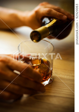 Hands pour a drink into a glass. 92920063
