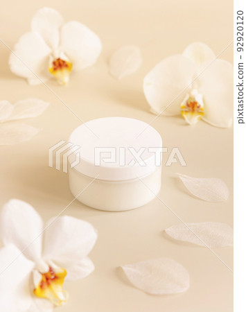 Cream jar with a blank white lid near orchid flowers on light yellow close up. Cosmetic Mockup Cream jar with a blank white lid near orchid flowers on light yellow close up. Cosmetic Mockup 92920120