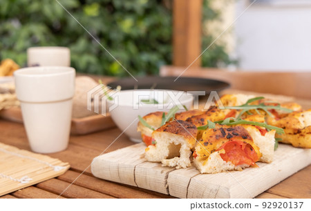 Tipical summer south Italian appetizer focaccia with cherry tomatoes and rucola served outdoor Tipical summer south Italian appetizer focaccia with cherry tomatoes and rucola served outdoor 92920137