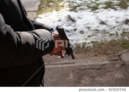 A man reloads a gun. Winter, out of the door, shooting range. Murder, danger, firearms. snow on the ground A man reloads a gun. Winter, out of the door, shooting range. Murder, danger, firearms. snow on the ground 92920348