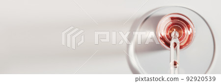 Oil or Serum bottle and pipette in petri dish on grey banner. Pink cosmetic product Oil or Serum bottle and pipette in petri dish on grey banner. Pink cosmetic product 92920539