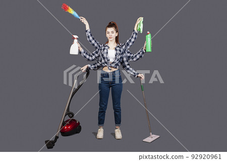 A girl on a gray background in the studio. isolate. A young woman with six hands, house. Vacuum, mop, detergent, dust collector, brush, rag. Robot machine for cleanliness. Cleaning company. Fast 92920961