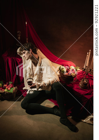 Creative portrait of young handsome man in image of famous historical character, medieval person isolated on dark vintage background. Retro style 92921221