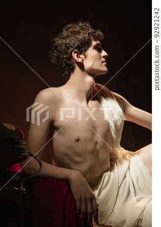 Mythology. Greek profile. Artistic portrait of young man in image of historical character, medieval person isolated on dark vintage background. Retro style Mythology. Greek profile. Artistic portrait of young man in image of historical character, medieval person isolated on dark vintage background. Retro style 92921242