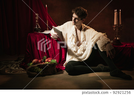 Artistic portrait of young handsome man in image of famous historical character, medieval person isolated on dark vintage background. Retro style Artistic portrait of young handsome man in image of famous historical character, medieval person isolated on dark vintage background. Retro style 92921256