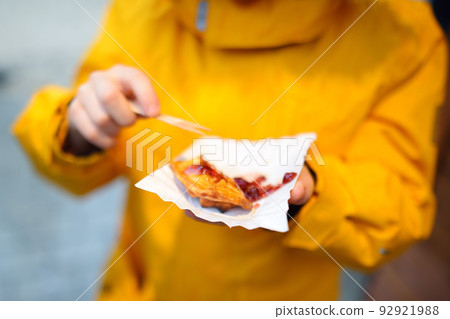 Child eating traditional Poland street food oscypek on Christmas market in Krakow. Oscypek is a grilled cheese of salted sheep milk with different ingredients as bacon or jams. Local cuisine. 92921988